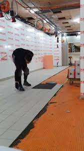 A Man Fixing the Floor of a Room With PVC Walls